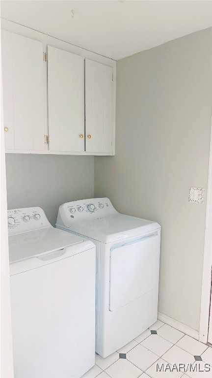 laundry area with cabinets, washer and clothes dryer, and light tile patterned flooring