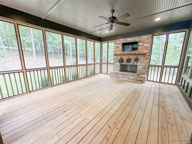 unfurnished sunroom with ceiling fan and a brick fireplace