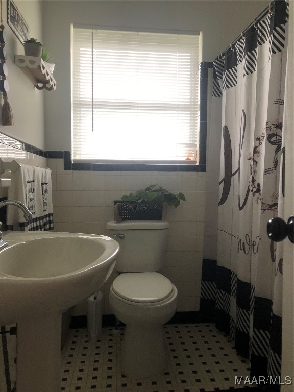 bathroom featuring a healthy amount of sunlight, tile walls, and toilet