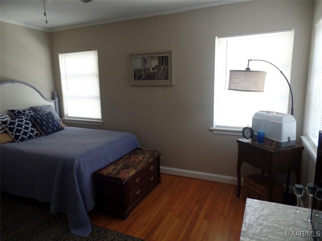 bedroom featuring ornamental molding, wood-type flooring, and multiple windows