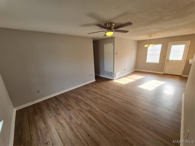 empty room with a textured ceiling, ceiling fan with notable chandelier, and light hardwood / wood-style flooring