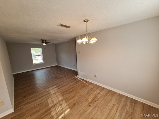 empty room with a textured ceiling, ceiling fan with notable chandelier, and hardwood / wood-style floors