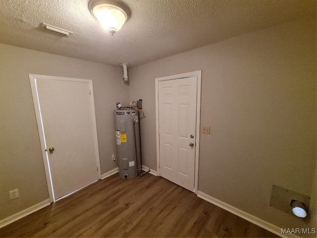 interior space with a textured ceiling, electric water heater, and dark hardwood / wood-style floors