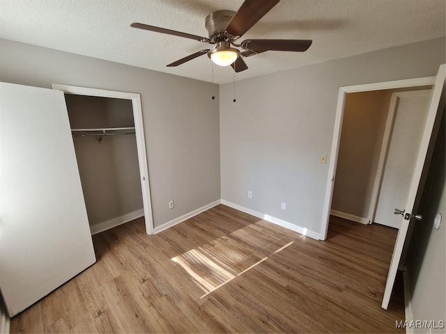 unfurnished bedroom featuring light wood-type flooring, a textured ceiling, ceiling fan, and a closet