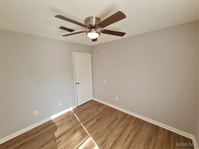 empty room with wood-type flooring, ceiling fan, and a textured ceiling