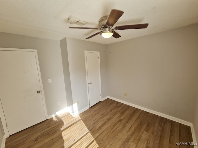 unfurnished bedroom featuring ceiling fan, hardwood / wood-style floors, and a textured ceiling