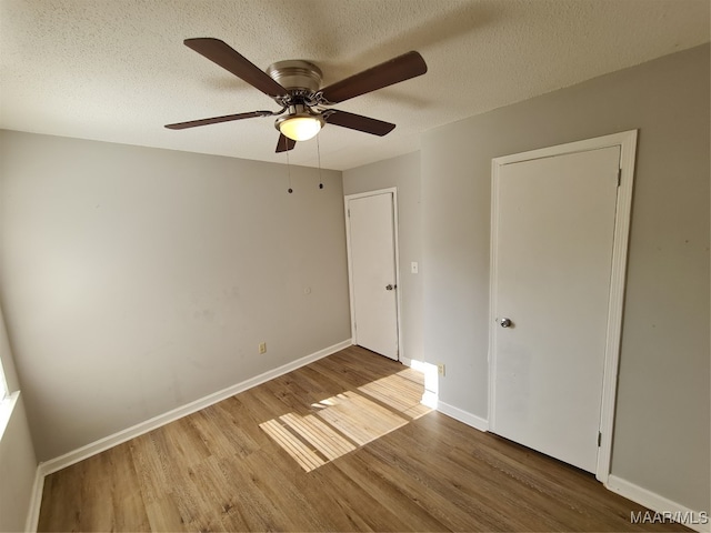 unfurnished bedroom with a textured ceiling, light hardwood / wood-style floors, and ceiling fan