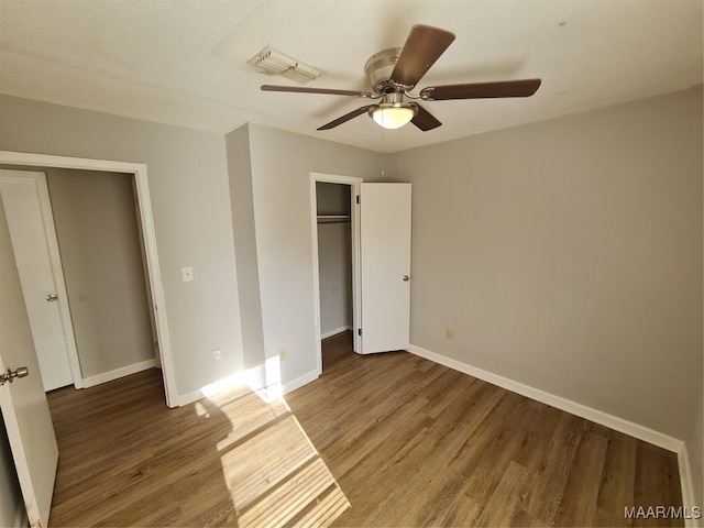 unfurnished bedroom with a textured ceiling, wood-type flooring, and ceiling fan