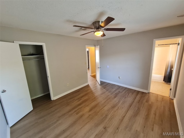 unfurnished bedroom featuring ceiling fan, a textured ceiling, a closet, and hardwood / wood-style floors