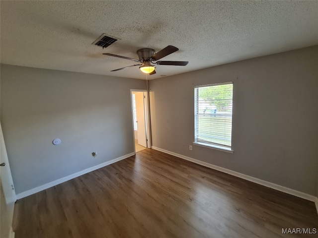 empty room with a textured ceiling, dark hardwood / wood-style flooring, and ceiling fan