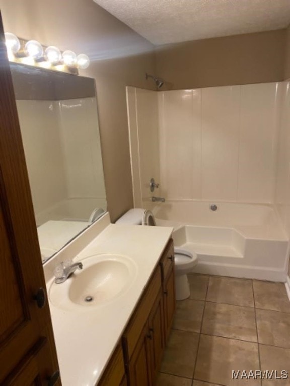 full bathroom with vanity, a textured ceiling, washtub / shower combination, tile patterned flooring, and toilet