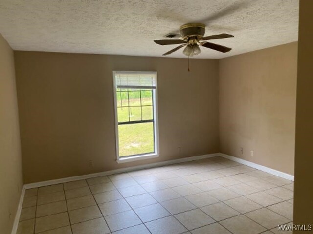 tiled empty room featuring ceiling fan and a textured ceiling