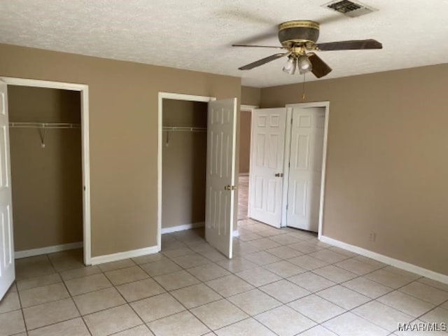 unfurnished bedroom featuring a textured ceiling, two closets, and ceiling fan