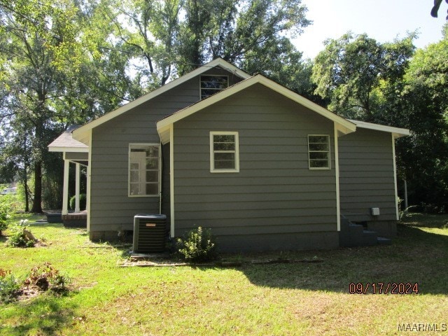 rear view of house featuring a lawn and central AC