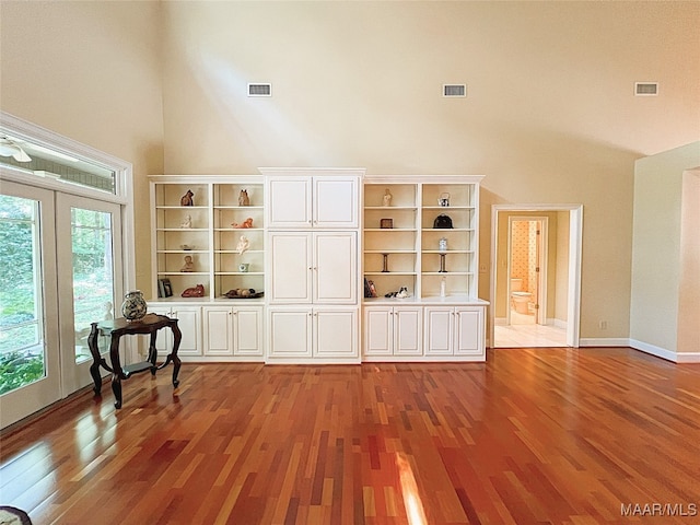 unfurnished living room with light hardwood / wood-style flooring and a towering ceiling