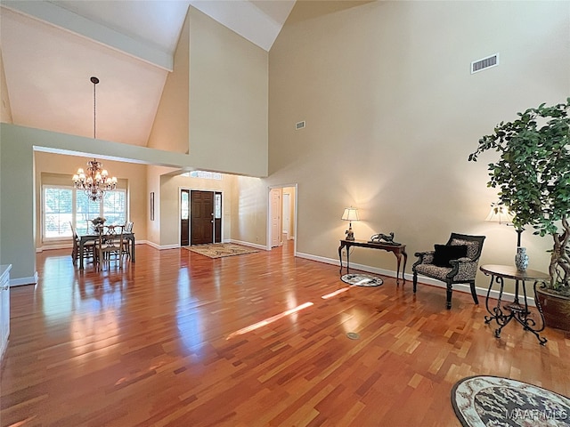 living room featuring beam ceiling, a chandelier, hardwood / wood-style floors, and high vaulted ceiling