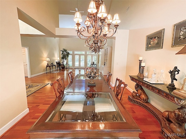 dining space featuring a high ceiling, a chandelier, hardwood / wood-style flooring, and french doors