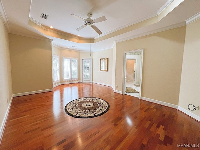 empty room featuring ornamental molding, a tray ceiling, ceiling fan, and hardwood / wood-style floors