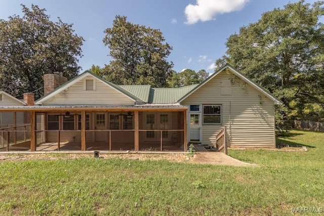 back of house with a patio area, a sunroom, and a lawn