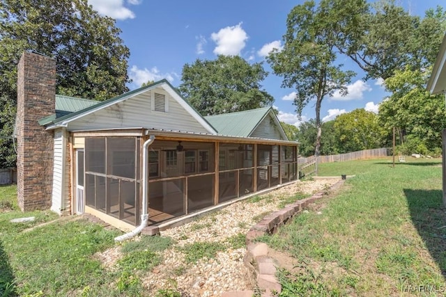 back of house featuring a sunroom and a lawn