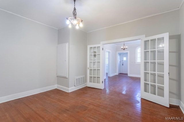 unfurnished room with wood-type flooring, an inviting chandelier, french doors, and crown molding