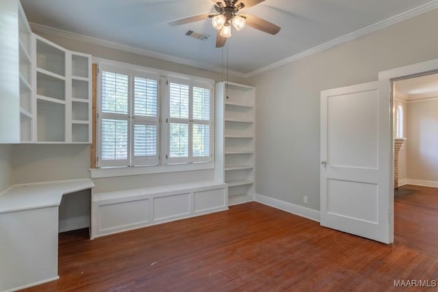 unfurnished office featuring ceiling fan, dark hardwood / wood-style flooring, crown molding, and built in desk