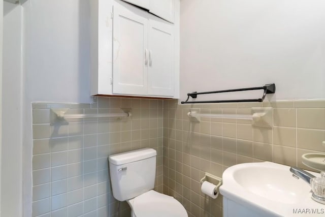 bathroom featuring sink, toilet, and tile walls