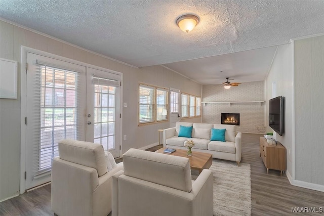 living room featuring a wealth of natural light, a brick fireplace, crown molding, and wood-type flooring