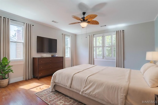 bedroom featuring light wood-type flooring, ceiling fan, and multiple windows