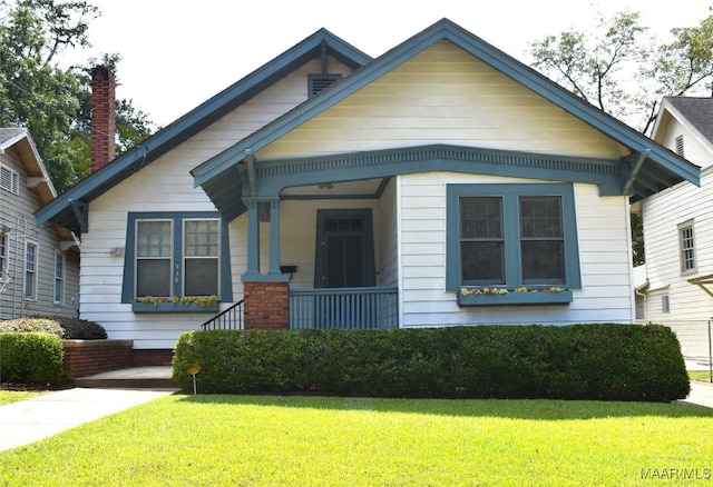 bungalow-style home with a front yard and covered porch