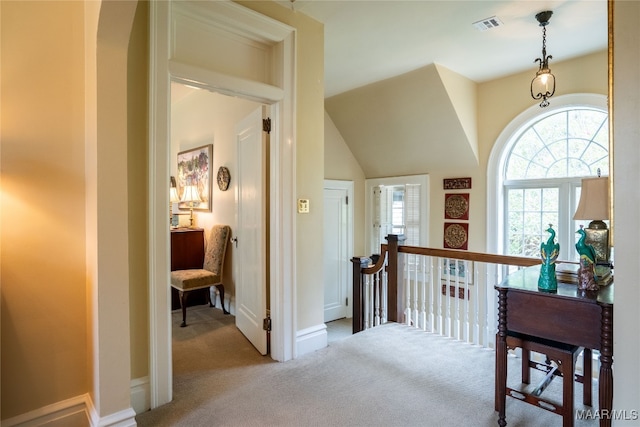 hallway featuring lofted ceiling and light carpet