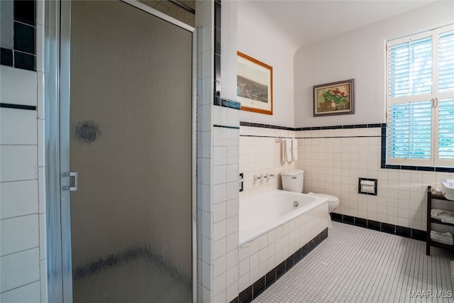 bathroom featuring shower with separate bathtub, tile walls, tile patterned flooring, and toilet