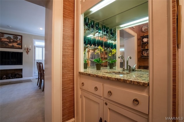 bar featuring ornamental molding, light stone countertops, sink, and light colored carpet