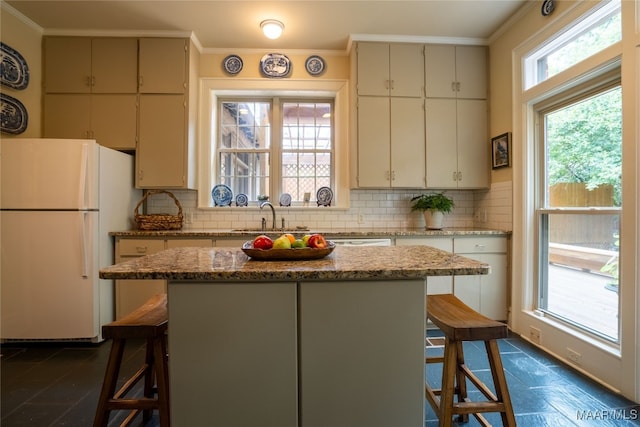 kitchen featuring white refrigerator, a kitchen island, and a breakfast bar area