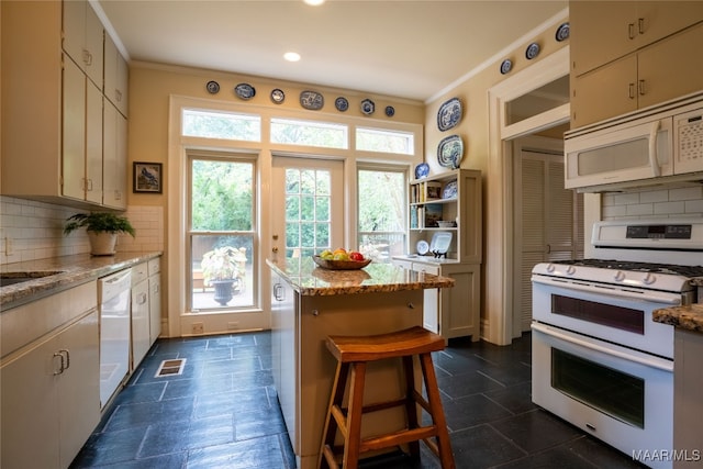 kitchen with light stone countertops, white appliances, plenty of natural light, and backsplash