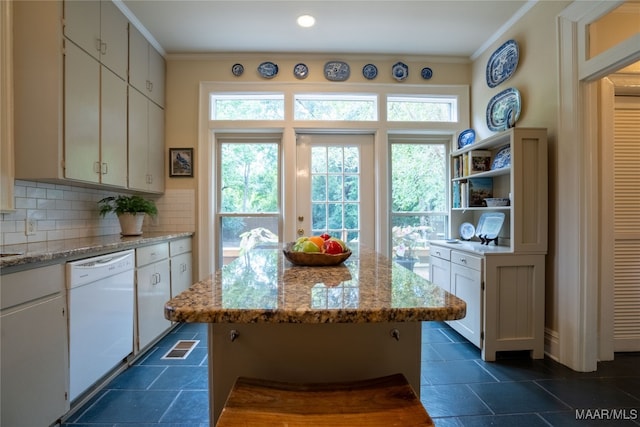 kitchen with light stone countertops, white cabinets, white dishwasher, and a center island