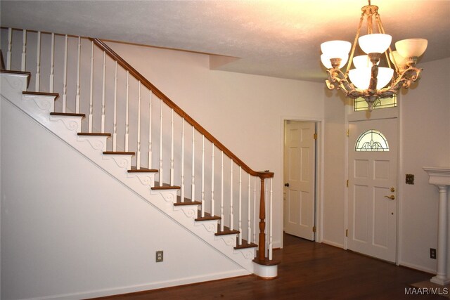 entrance foyer with a notable chandelier, a textured ceiling, and dark wood-type flooring