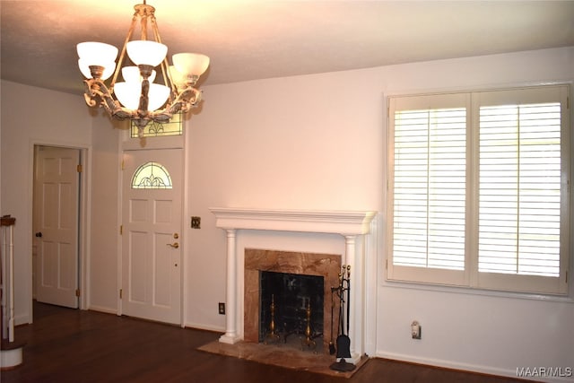 unfurnished living room featuring a notable chandelier, a premium fireplace, and dark hardwood / wood-style flooring