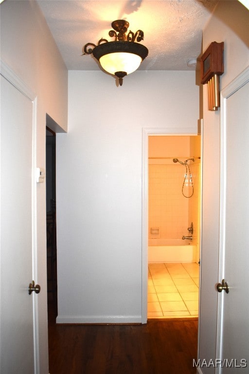 corridor with a textured ceiling and dark hardwood / wood-style floors