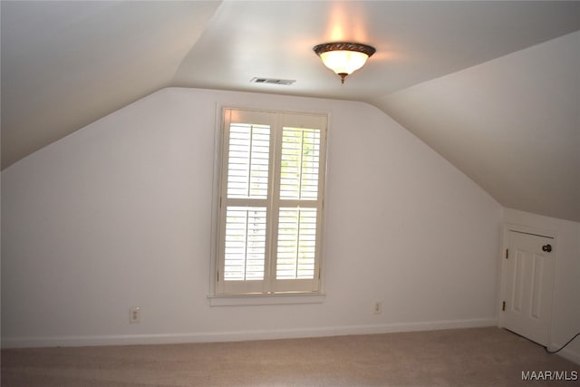 additional living space featuring vaulted ceiling and carpet flooring