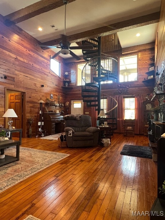 living room with hardwood / wood-style flooring, wooden walls, and beamed ceiling