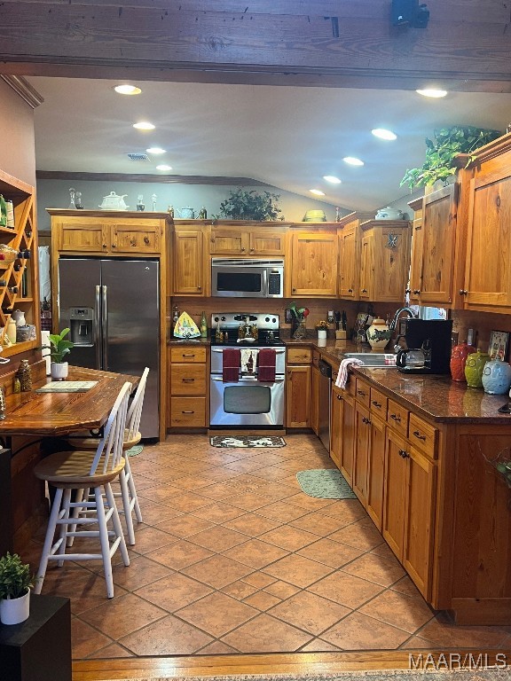 kitchen featuring lofted ceiling, sink, light tile patterned floors, dark stone countertops, and stainless steel appliances