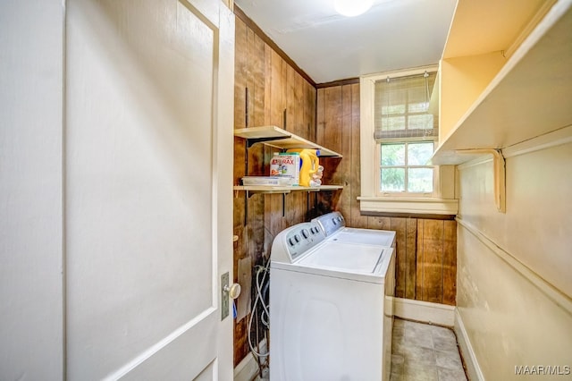 laundry area with wooden walls and independent washer and dryer