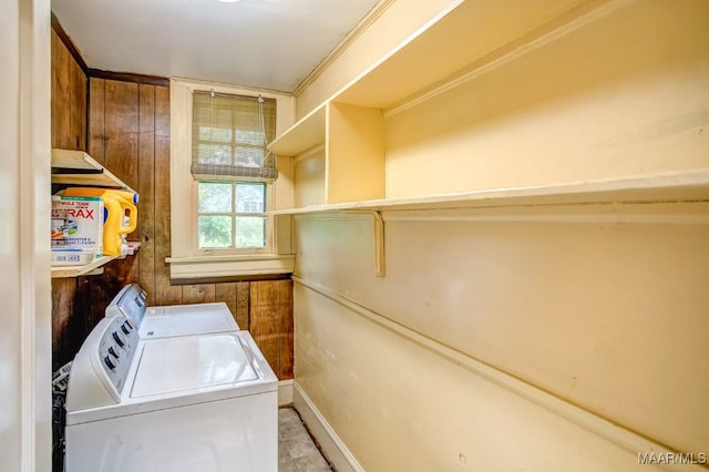 washroom featuring washing machine and dryer and wood walls