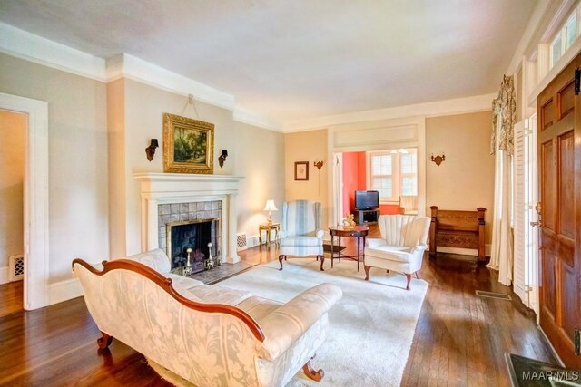 living room featuring crown molding, dark hardwood / wood-style flooring, and a tile fireplace