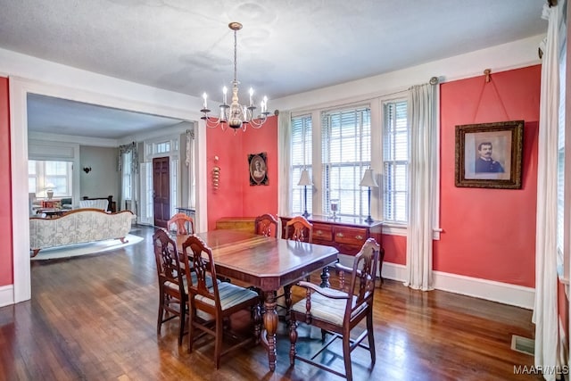 dining area with a chandelier, a textured ceiling, and dark wood-type flooring