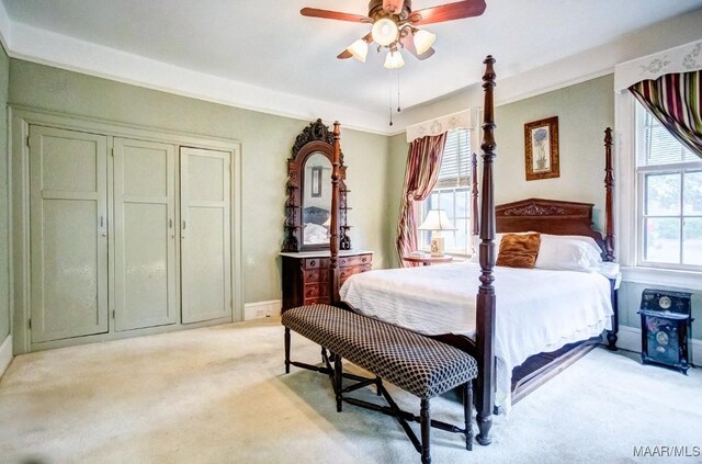 carpeted bedroom featuring multiple windows and ceiling fan