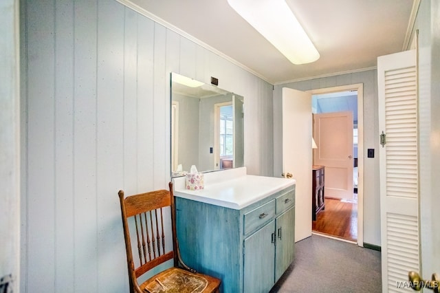 bathroom featuring ornamental molding, wood walls, hardwood / wood-style floors, and vanity