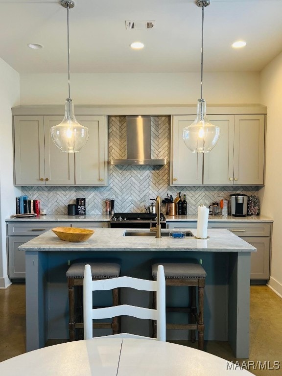 kitchen featuring wall chimney exhaust hood, a kitchen breakfast bar, hanging light fixtures, and tasteful backsplash