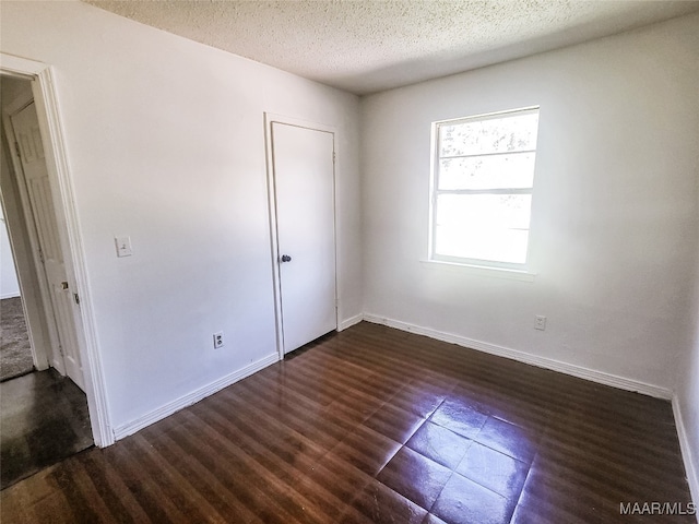 spare room with a textured ceiling and dark hardwood / wood-style flooring